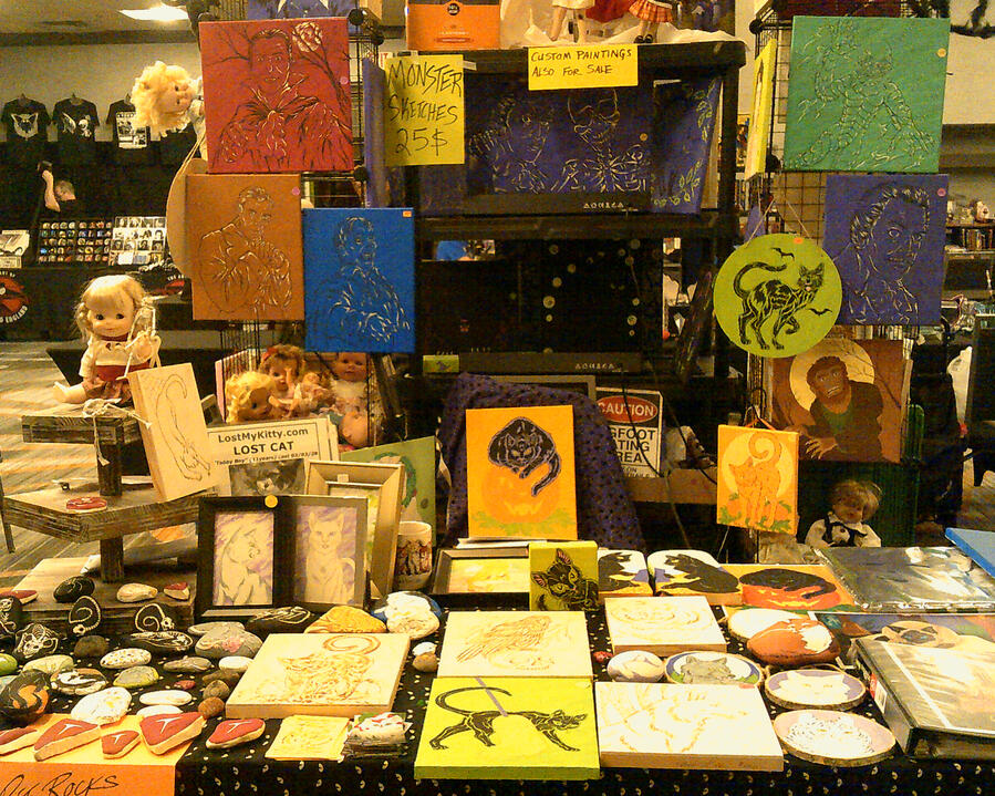 My creepy horror and Halloween wares. Note the big, hairy spiders and creepy dollies peeping around the corners. Pieces at this show included blacklight art, lots of black cat art and classic horror-genre actor paintings.